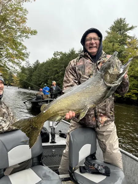 Angler holding a large salmon aboard a drift boat