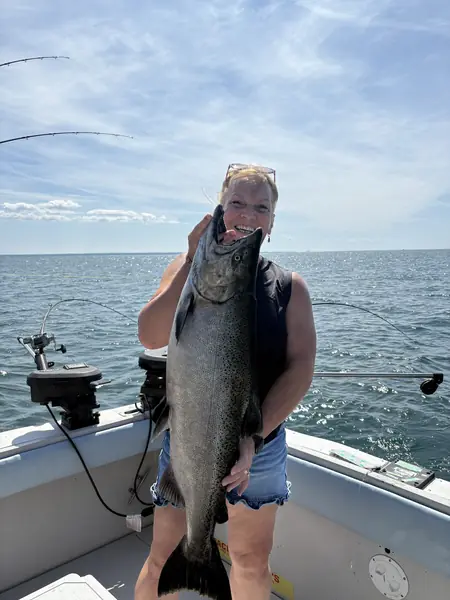 Angler holding a large salmon on a charter boat on open water