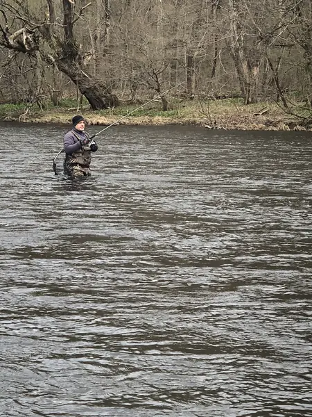 Angler wading a river with a fly rod
